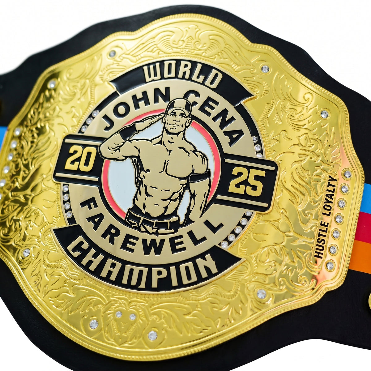 A close-up of a championship belt featuring a large ornate gold plate with the text 'WORLD JOHN CENA FAREWELL CHAMPION 2025' and an illustration of John Cena saluting. The belt includes black sections, decorative scrollwork, small rhinestone accents, and a multicolor stripe along the side edge.
