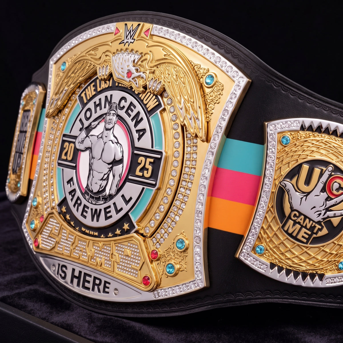 A close-up of a custom wrestling championship belt featuring John Cena graphics, with gold and silver plates, rhinestone accents, and a black strap with teal, pink, and orange stripes.