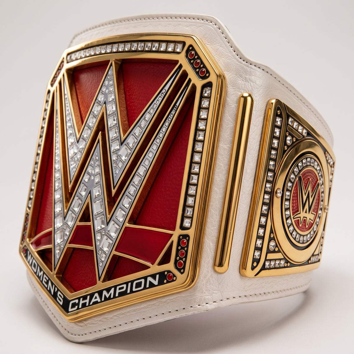 A WWE Women's Champion belt with a large red and gold central plate, silver and crystal-embellished 'W' logo, and a white textured strap on a light gray background.