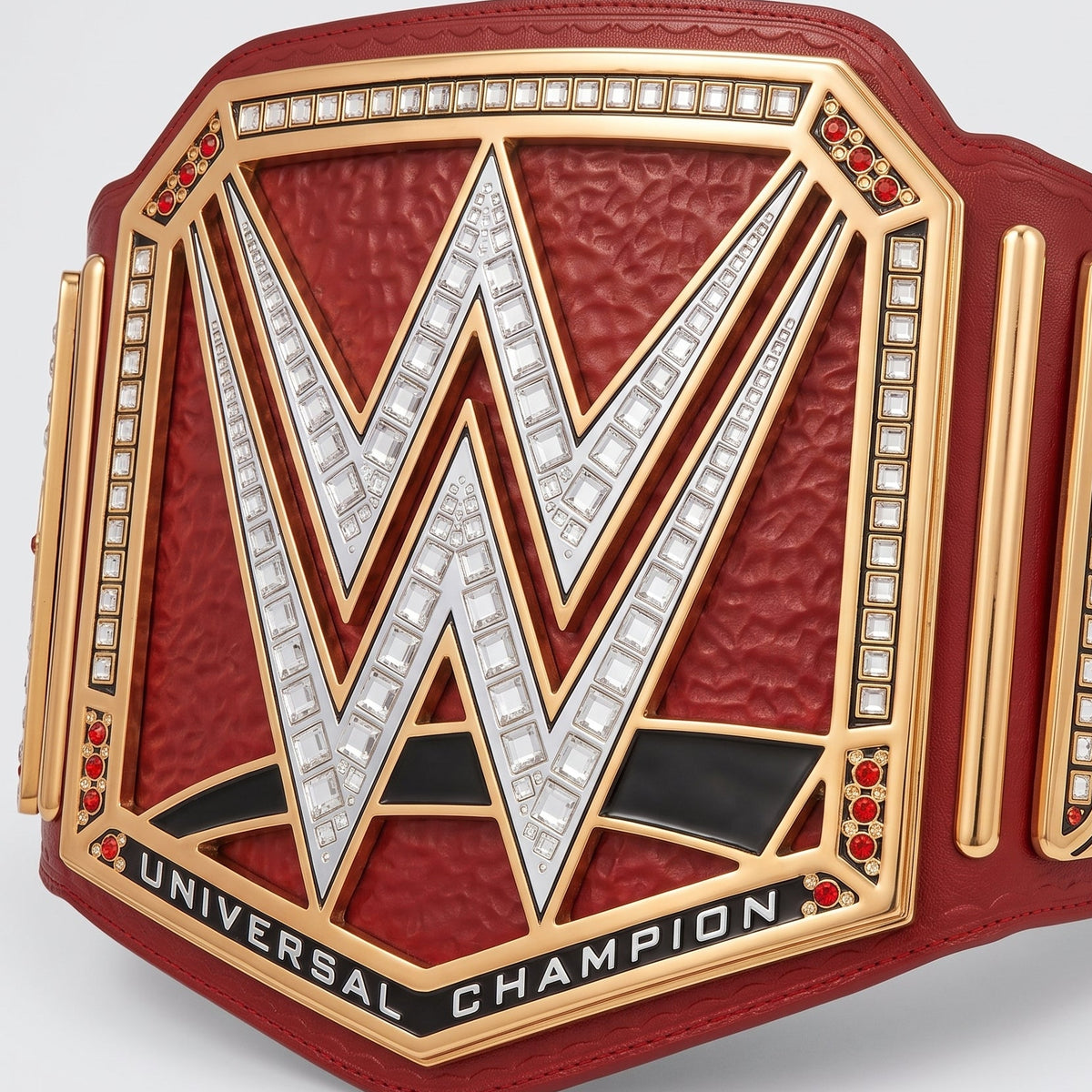 A WWE Universal Champion belt with a textured red leather strap, gold-plated metal plates, and silver crystal-embellished 'W' logo on a light gray background.
