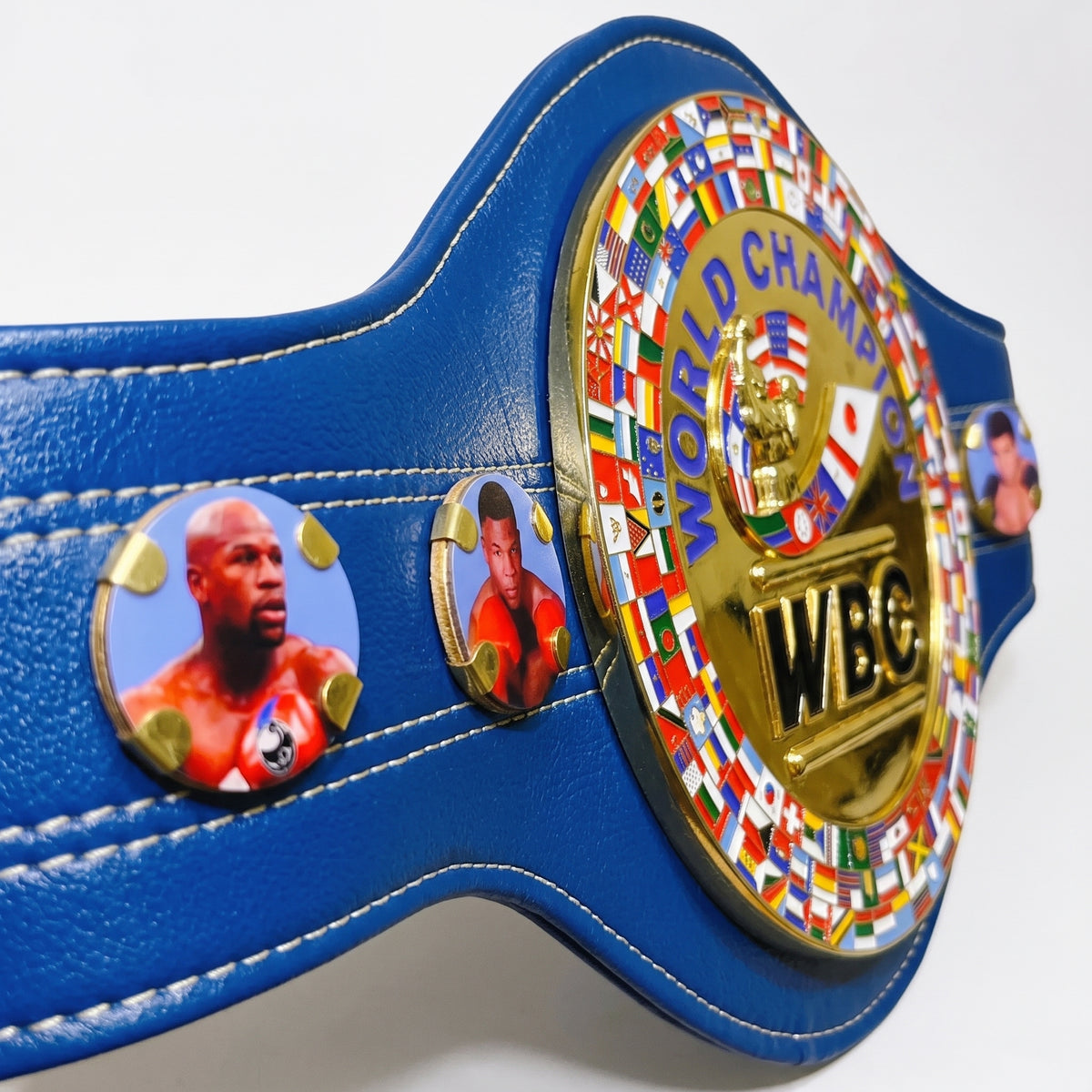 A blue leather championship belt with gold-tone hardware, featuring circular medallions including a large 'WBC' emblem and smaller portrait medallions, photographed on a white background.