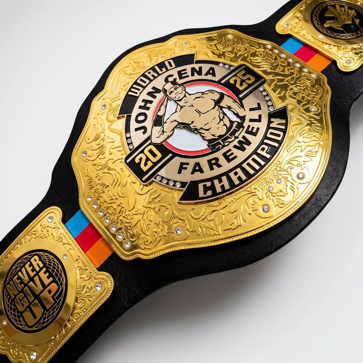A close-up of a replica championship belt featuring a large gold central plate with 'World John Cena 63 Farewell Champion' text and a central figure of John Cena, mounted on a black strap with a blue, red, and orange stripe.