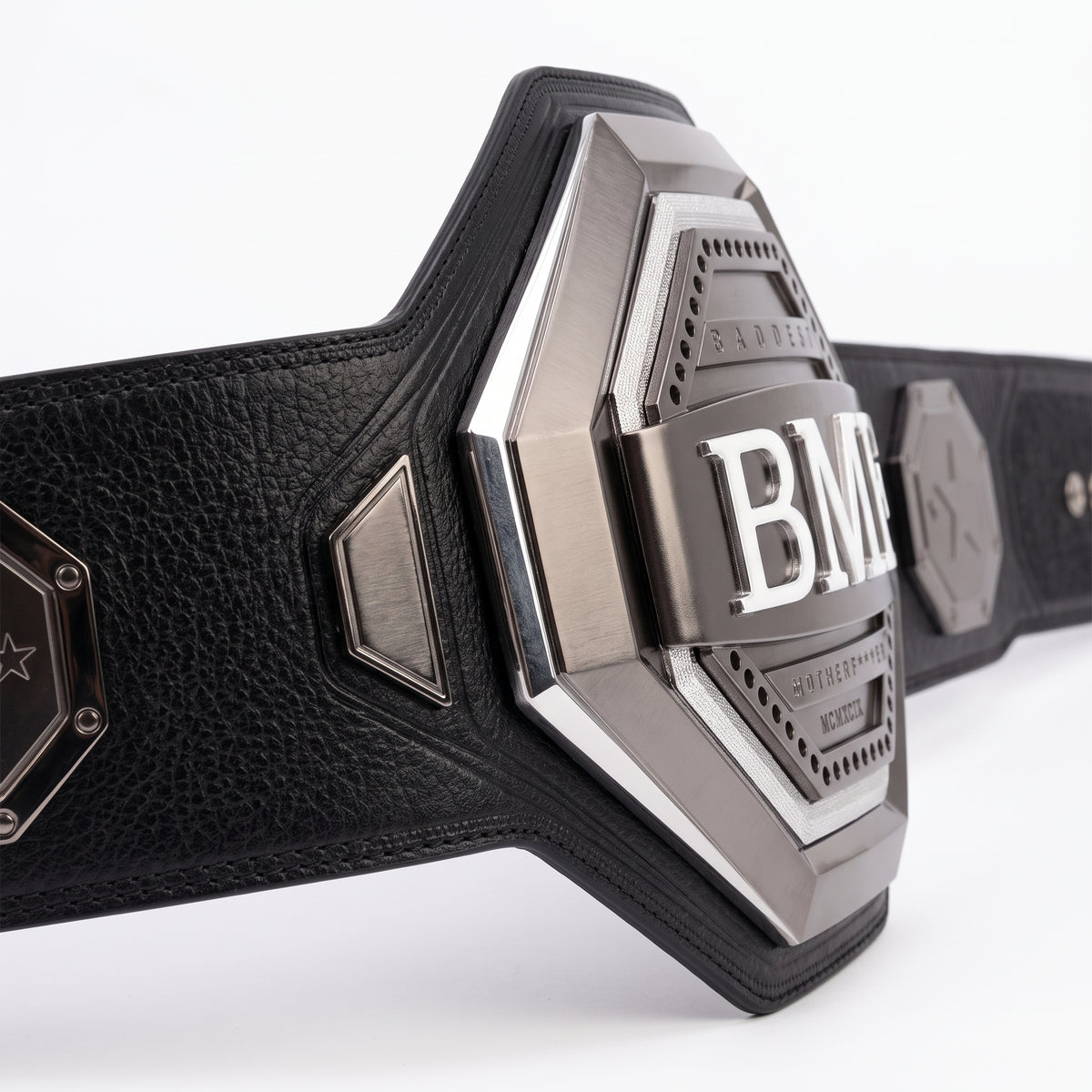 A close-up of a black leather belt with a large metallic silver buckle featuring the letters 'BM' and 'BOSTON MAINTENANCE' on a white background.