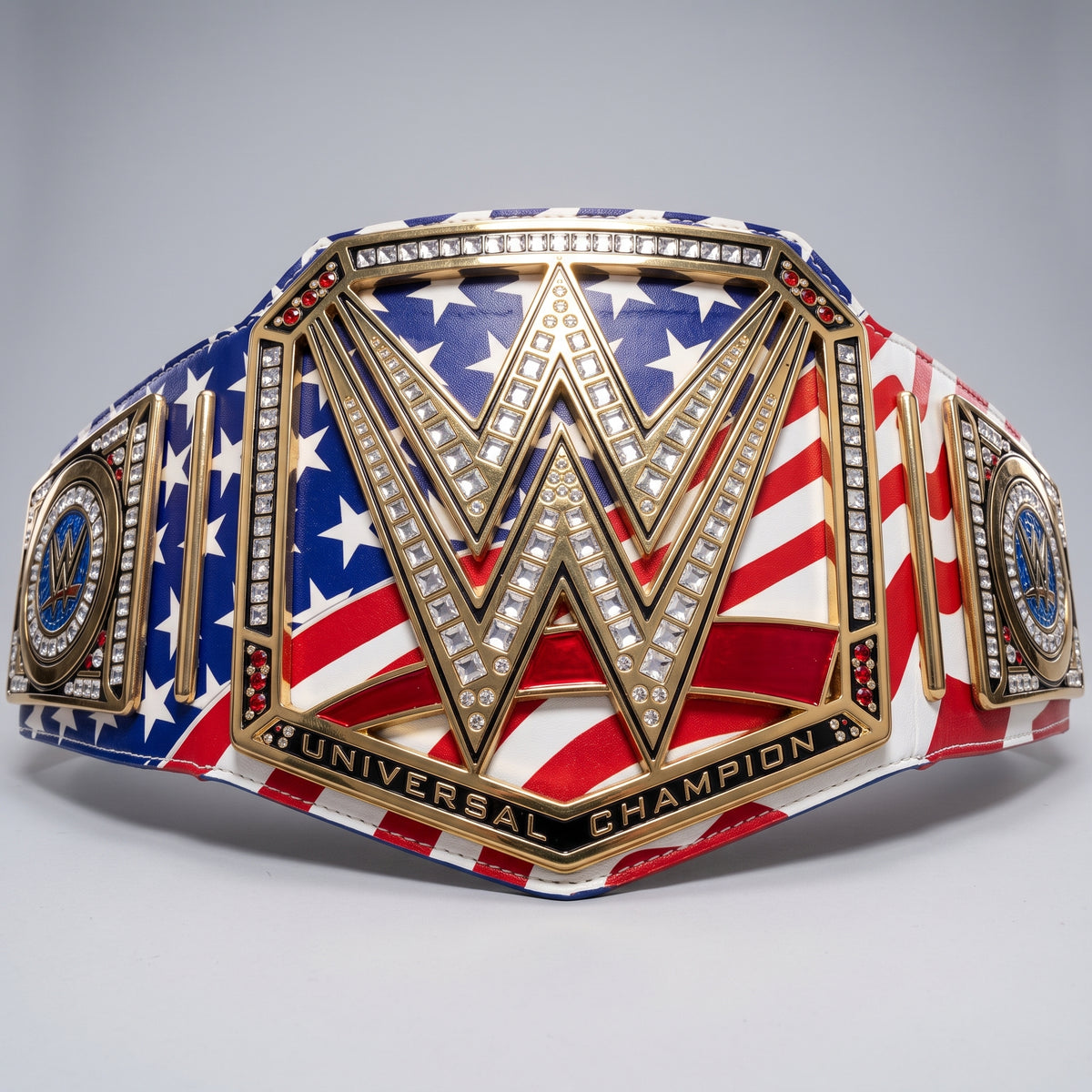 A WWE Universal Champion belt featuring an American flag design with red and white stripes, white stars on blue, and gold-toned metal detailing with clear rhinestones.