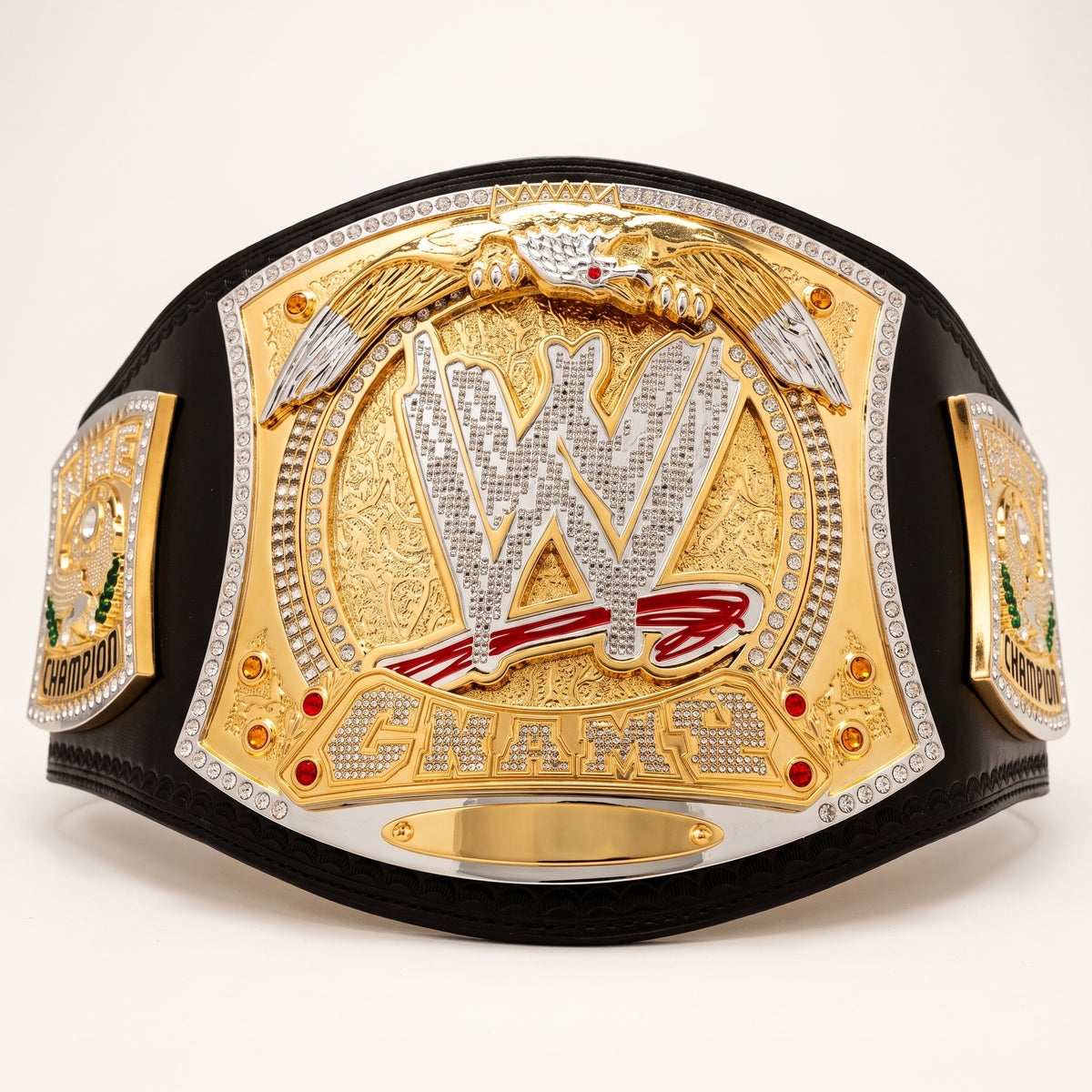 A WWE Championship belt with a large gold and silver central plate, black leather strap, and detailed side plates, photographed on a clean white background.