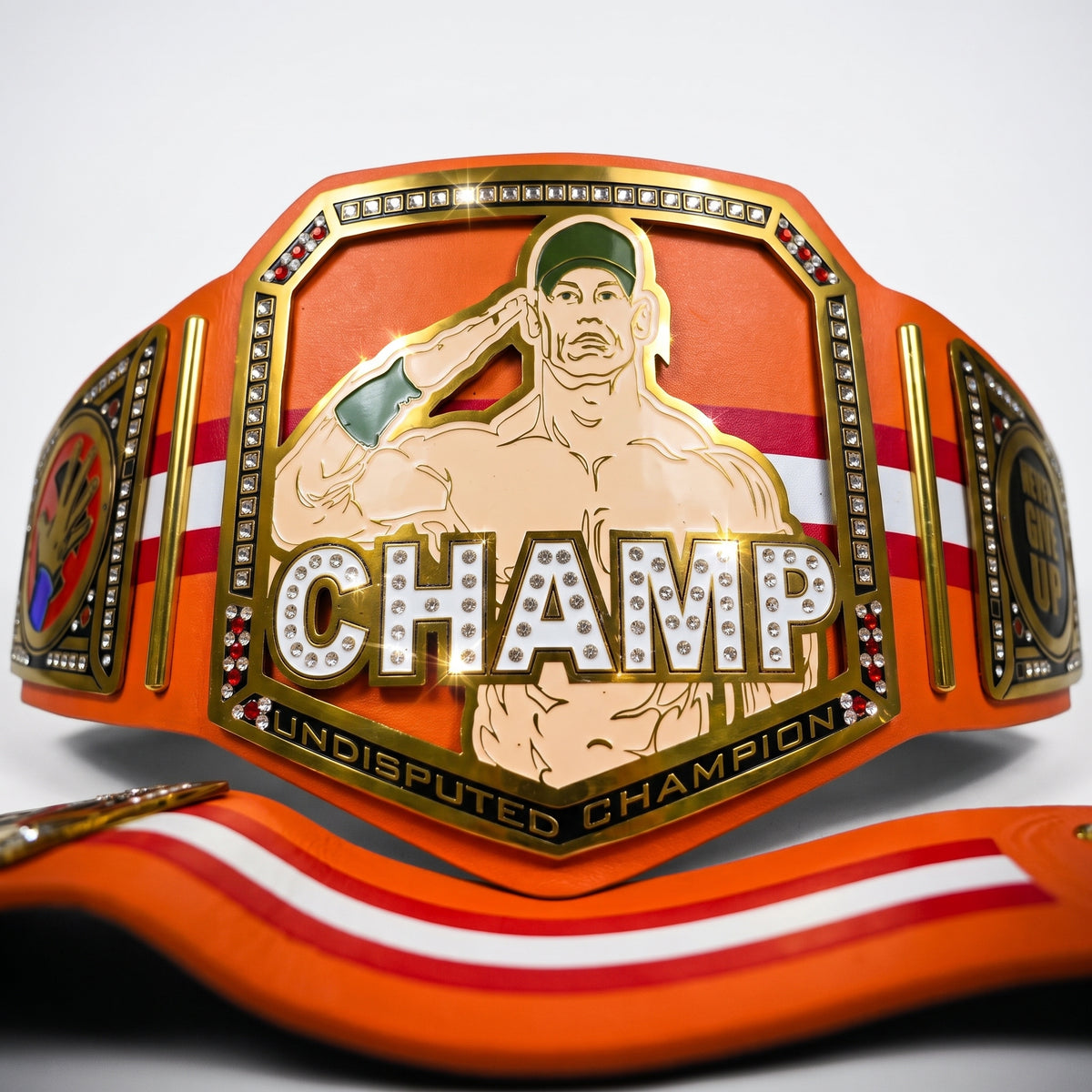 An orange and gold championship belt with a central plaque featuring a saluting wrestler silhouette and the word 'CHAMP' in rhinestone letters, shown on a white background with part of the matching orange and white strap visible in front.